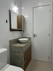 y baño con lavabo, aseo y espejo. en Apartamento Fátima PARA FAMÍLIA, en Balneário Camboriú