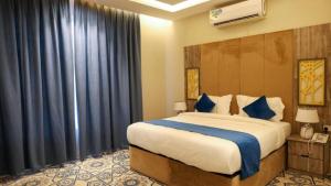 a bedroom with a large bed with blue curtains at برج بيات in Jazan