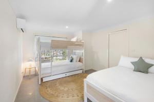 a white bedroom with a bed and a bunk bed at Bombora in Lennox Head