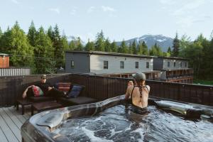 a young man in a hot tub on a patio at The Nest - Condo with Hot Tub & BBQ in Revelstoke