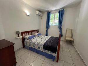 - une chambre avec un lit doté de rideaux bleus et d'une fenêtre dans l'établissement Maison type F4 vue sur mer, au Gosier
