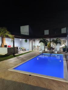 a large blue swimming pool in a yard at night at Casa Lenger in Aracaju