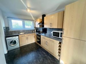 cocina con armarios de madera, lavadora y secadora en Spacious 2 double bed city home, en Hereford