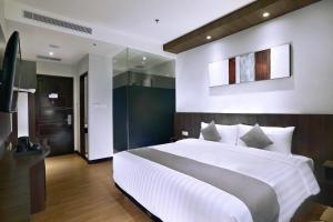 a bedroom with a large white bed and a mirror at Neo Dipatiukur Bandung by ASTON in Bandung