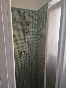 y baño con ducha y pared de azulejos verdes. en Sara House Palermo, en Palermo