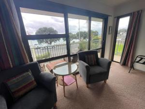 a living room with a table and chairs and a large window at Bay Sands Seafront Studios in Paihia