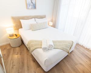 Un dormitorio con una gran cama blanca con toallas. en Sandcastles Mooloolaba, en Mooloolaba