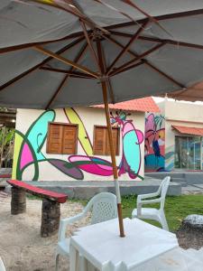 uma mesa com um guarda-chuva em frente a uma parede com graffiti em Temporada Ilhéus Olivença em Ilhéus