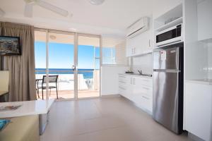 a kitchen with a refrigerator and a view of the ocean at Sandcastles Mooloolaba in Mooloolaba