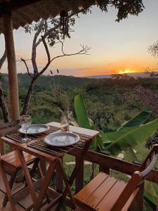 a wooden table with two glasses of wine and a sunset at Casa confortável, pertinho da cidade e conectada a natureza in Brasília