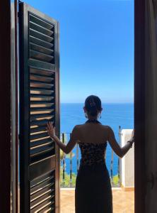 Eine Frau, die aus dem Fenster auf den Ozean schaut. in der Unterkunft Villa Rosanna in Massa Lubrense