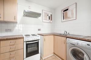 eine Küche mit einer Waschmaschine und einem Waschbecken in der Unterkunft Docklands Cozy View Apartment in London