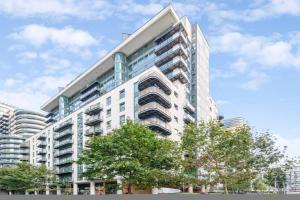 a tall building with trees in front of it at Docklands Cozy View Apartment in London