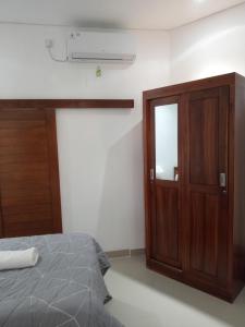 1 dormitorio con 1 cama y armario de madera en Chida Homestay, en Ubud