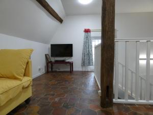 ein Wohnzimmer mit einem Sofa und einem TV in der Unterkunft Gîte Garnay, 3 pièces, 4 personnes - FR-1-581-103 in Garnay