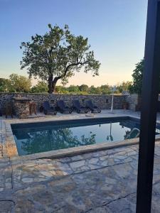 una piscina con sedie accanto a un muro di pietra di Family friendly house with a swimming pool Benkovac, Zagora - 21720 a Benkovac (Bencovazzo)