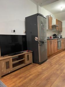 a kitchen with a black refrigerator and a tv at Transformative housing Exeter Road in Nottingham