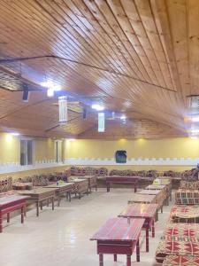 una grande stanza con tavoli e sedie in legno di Sunrise Wadi Rum Camp a Wadi Rum