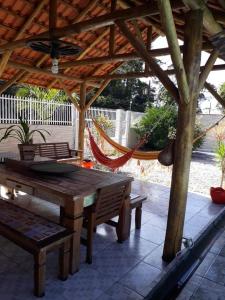 a patio with a hammock and a wooden table and bench at Casa de ferias in Barra Velha