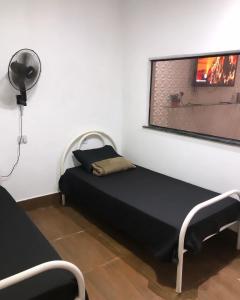 a bedroom with a bed and a window with a fan at Casa de temporada Xerém in Duque de Caxias