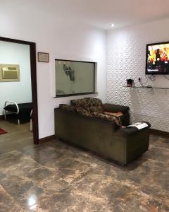a living room with a couch and a flat screen tv at Casa de temporada Xerém in Duque de Caxias