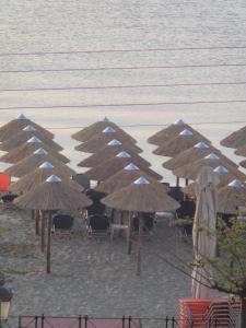 a group of straw umbrellas on a beach with the water at Villa Nikolas in Paralia Katerinis