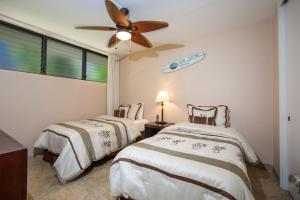 2 Betten in einem Zimmer mit Deckenventilator in der Unterkunft Maui Parkshore 105 - MCH in Kihei