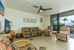 ein Wohnzimmer mit einem Sofa, Stühlen und einem TV in der Unterkunft Maui Parkshore 312 - MCH in Kihei