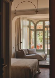a bedroom with a bed and a couch in front of a window at Casa Llimona Hotel Boutique in Barcelona +64 photos