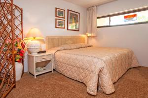 a bedroom with a bed and a lamp and a window at Sugar Beach 223 - MCH in Kihei