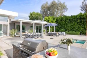 een achtertuin met een grill en een tafel met fruit bij Polo Villa 1 by AvantStay Features Expansive Pool, Spa & Outdoor Firepit 260-322 5 Bedrooms in La Quinta