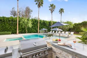 een buitenkeuken met een grill en een zwembad bij Polo Villa 1 by AvantStay Features Expansive Pool, Spa & Outdoor Firepit 260-322 5 Bedrooms in La Quinta