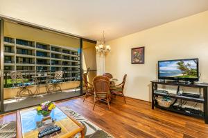 a living room with a television and a table with chairs at Sugar Beach 301 - MCH in Kihei