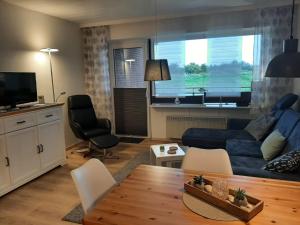 a living room with a blue couch and a table at Fewo Am Deich 1 Appartment 30 in Sankt Peter-Ording