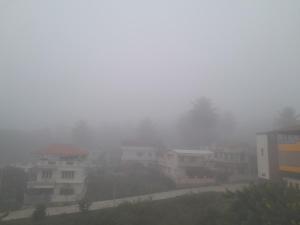 una ciudad en la niebla con casas y edificios en Lucky Inn Coorg, en Kushālnagar