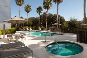 einen Pool mit einem Tisch, Stühlen und Palmen in der Unterkunft Springhill Suites Jacksonville in Jacksonville