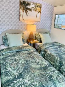 two beds in a room with palm trees at Mornington Peninsula Retro Caravans in Rye