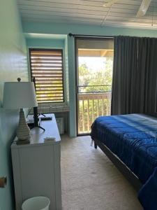 um quarto com uma cama e uma secretária com um candeeiro em Turtle Bay Sage TA-097-866-3424-02 condo em Kahuku