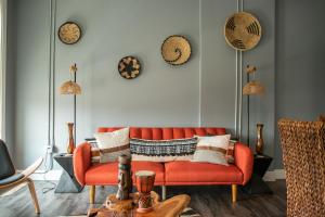 a living room with an orange couch and clocks on the wall at The Sahara #3 in Bellefontaine