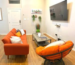 a living room with an orange couch and a table at NEW! Luxury Apt, 5 min from Mall, Airport, & Dine! in McAllen