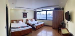 een slaapkamer met 2 bedden en een televisie. bij TUONG MAI HOTEL in Sa Pa