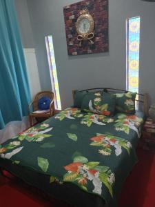 a bed with a green comforter and a clock on the wall at Homestay ALHAQIM in Pontian Kecil