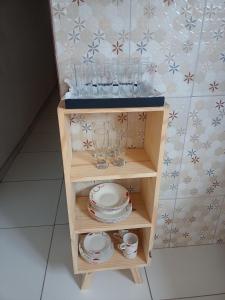 uma pequena prateleira de madeira com pratos e copos em Aconchego da Kika em Caruaru
