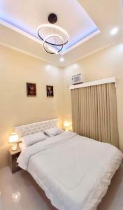 a bedroom with a large white bed with a blue light at Lemoons Apartelle in Tagum