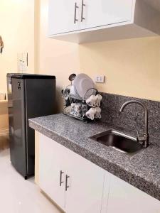 a kitchen with a sink and a black refrigerator at Lemoons Apartelle in Tagum