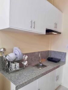 a kitchen counter with a sink and white cabinets at Lemoons Apartelle in Tagum