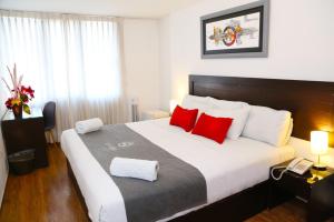 1 dormitorio con 1 cama grande con almohadas rojas en Hoteles Riviera Ejecutivo en Arequipa