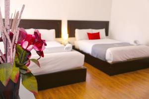 a hotel room with two beds and a vase with flowers at Hoteles Riviera Ejecutivo in Arequipa