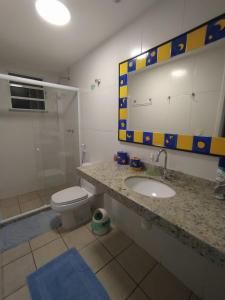 een badkamer met een wastafel, een toilet en een spiegel bij Cabo Frio- Casa pé na areia - Suíte vista mar- Garagem coberta privativa 2 vagas in Cabo Frio