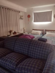 two beds in a bedroom with a plaid couch at Mar de Cobo casa en alquiler temporario in Mar de Cobo